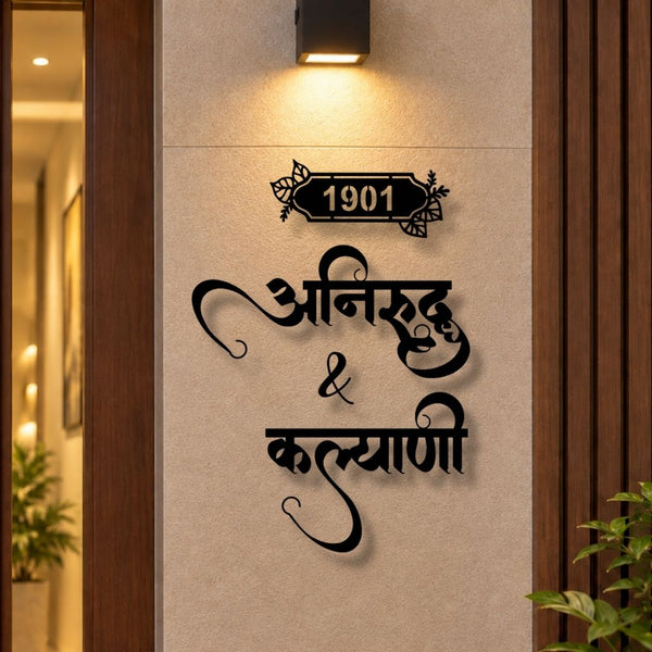 Black metal wall art featuring the number 1901 in a decorative plaque above stylized Devanagari script, mounted on a beige textured wall under a lit sconce.

