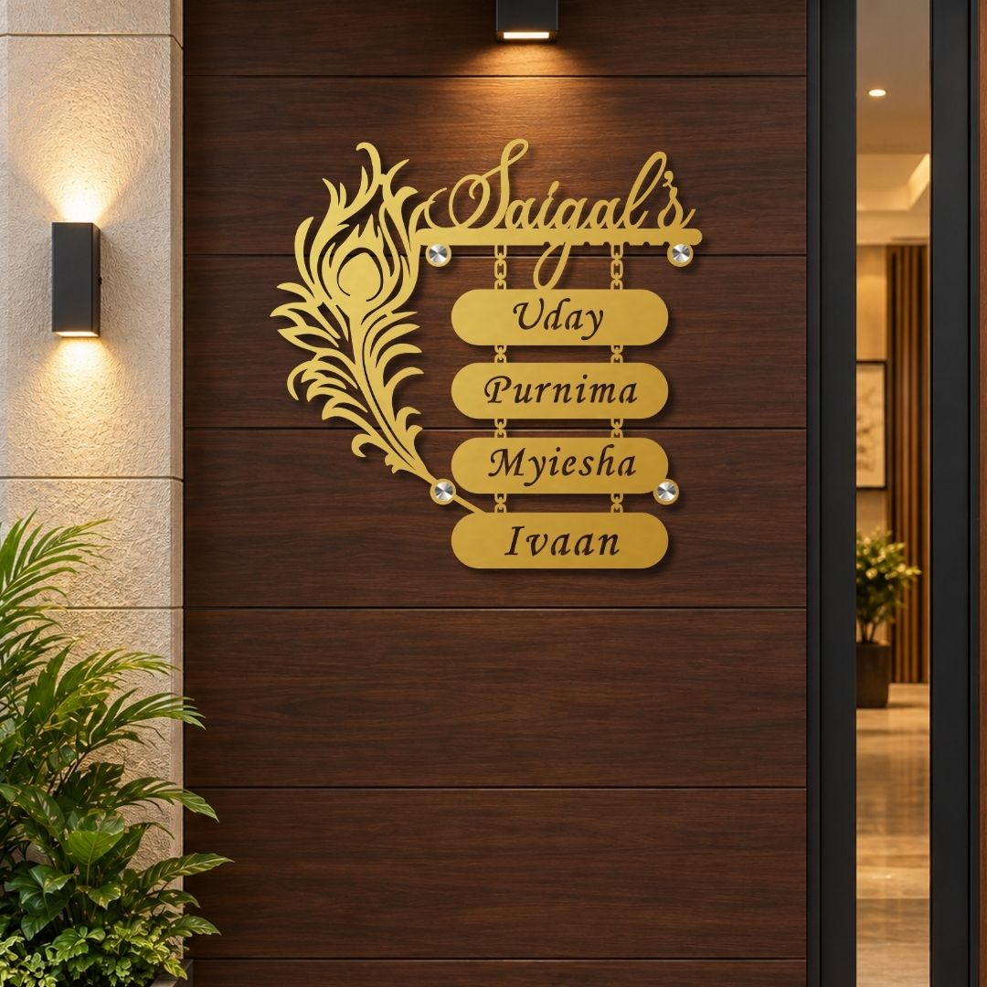 A personalized gold metal wall sign mounted on a dark brown wooden door. The sign features a decorative peacock feather on the left, the script name 'Saiyaal's' at the top, and four horizontal nameplates spelling 'Uday', 'Purnima', 'Myiesha', and 'Ivaan'.

