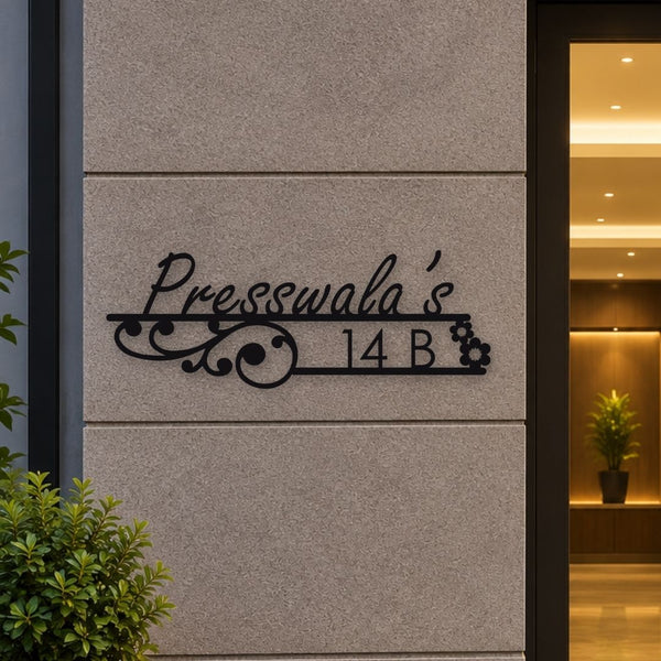 Black metal custom sign reading 'Presswala's 14 B' mounted on a light gray stone wall next to a doorway.

