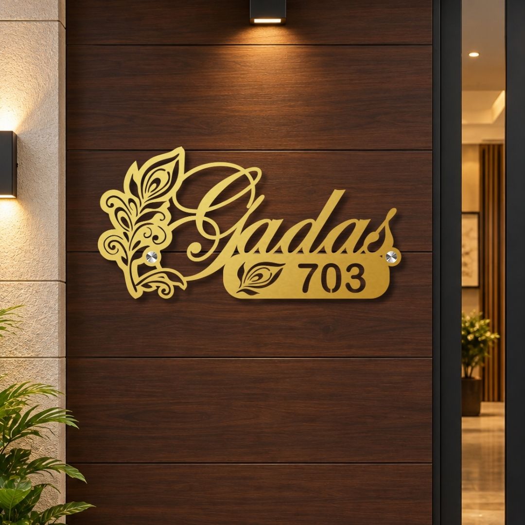 Gold metal house number sign reading 'Gadas 703' with decorative leaf flourishes, mounted on a dark wood-paneled exterior wall.