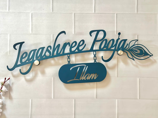 A teal metal custom wall sign featuring the script name 'Dolly' with a hanging number plate reading '230/3' and an arrow motif, mounted on a beige tiled wall under a black wall sconce.